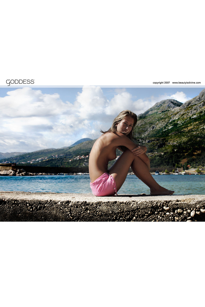 Стройная девушка с торчащими сосками в трусиках фотографируется около океана